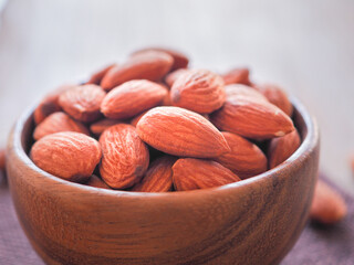 Organic almonds seed in wooden bowl on sackcloth. Colse up. Healthy food..