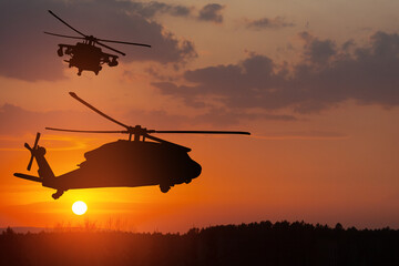 Silhouettes of helicopters on background of sunset.