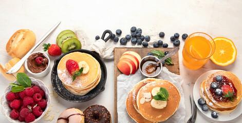 Fototapeta na wymiar Pancakes with fresh fruits, donuts and coffee on a white background.