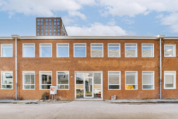 a red brick building with white trim around the window panes and sky in the background, taken from outside