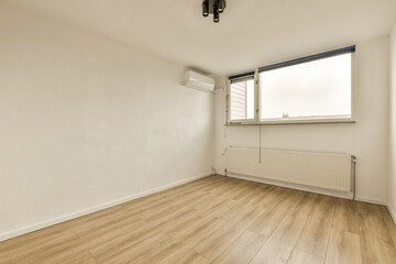 an empty room with wood flooring and white walls, there is a window that looks out onto the street