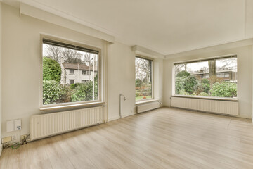 an empty living room with wood flooring and large windows looking out onto the trees outside in the backyard area
