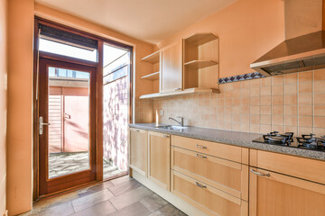 a kitchen with wood cabinets and tile flooring in an apartment or residential area looking out to the backyard patio