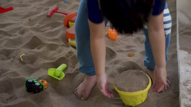 4K, Asian boy playing on pile sand grounds house, asian boy playing on pile sand on grounds his house, use scoop scoop up sand pour it into mold, boy lifted sand play in back after sand shoveling.