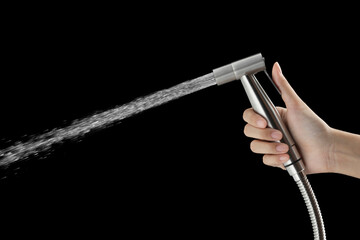 Woman hand using bidet shower head on black