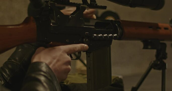 Hand closing bolt of FN FAL combat rifle at shooting range and taking aim