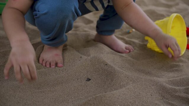 4K, boy's two hands close up, sitting down with pile loose sand, used both hands pick it up fill sand by hand, in order lift it up into shape as high as mountain, made crumbly sand.