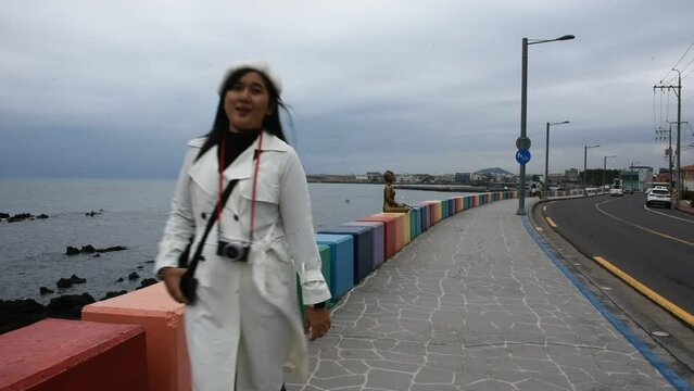 Travelers thai women people travel visit and take photo landmarks sightseeing colored barrier and landscape sea ocean of Dodu dong rainbow coastal road on February 17, 2023 in Jeju Island, South Korea