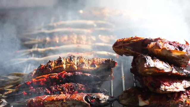 Selective focus of cooking fish. Baking and roasting marinated fish on barbecue grill. Thunnini grilled over charcoal. Summer barbeque hand marinade the fish.