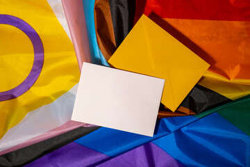 Empty paper blank on Rainbow LGBTQIA flag made from silk material. Mock up template copy space for...