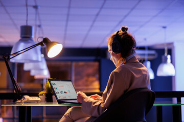 Careful businesswoman analyzing financial graphs report on computer, typing company strategy...