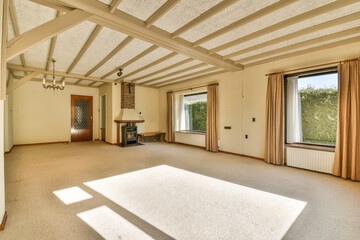 an empty living room with wood beams on the ceiling and large windows overlooking out onto the landscaped garden area