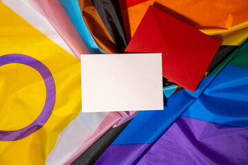 Empty paper blank on Rainbow LGBTQIA flag made from silk material. Mock up template copy space for your text. Symbol of LGBTQ pride month. Equal rights. Peace and freedom. Support LGBTQIA community