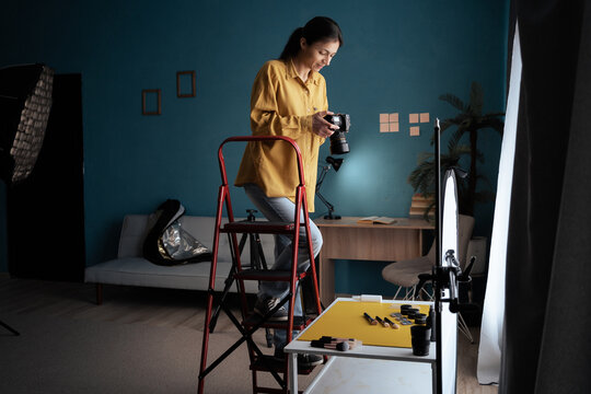 Female photographer setting up camera in home studio. Modern blogger. Content creator. Woman shooting photos.
