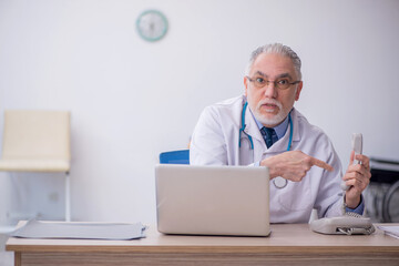 Old male doctor in telemedicine concept