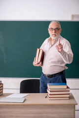 Old male teacher sitting in the classroom