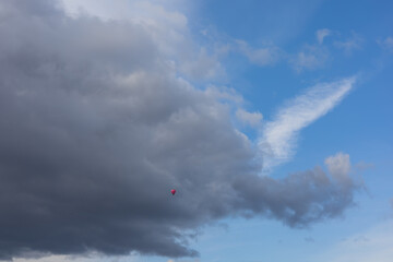 Pink flying balloon on blue sky with clouds.