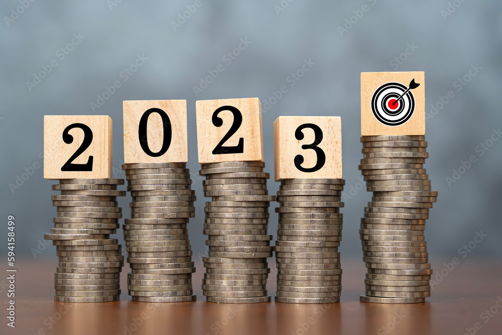 Aufkleber 2023 wooden cube and target on stack of coins with dark background and copy space. money saving idea