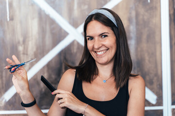 Cool hairdresser smiling and holding scissors and comb