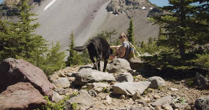 Girl and black lab taking a break on mountain hike