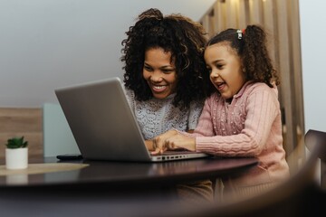 Fototapeta na wymiar Smiling african american mother and daughter using laptop at home