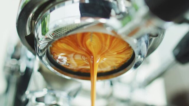 Coffee espresso machine pulling double shot espresso from bottomless naked portafilter. Professional equipment at cafe. Zoom in Closeup.