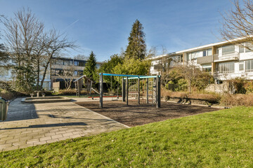 a park area with some buildings in the background and a playground set up for children to play on the grass