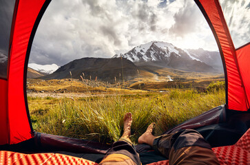 Man relaxing in his tent in the mountains