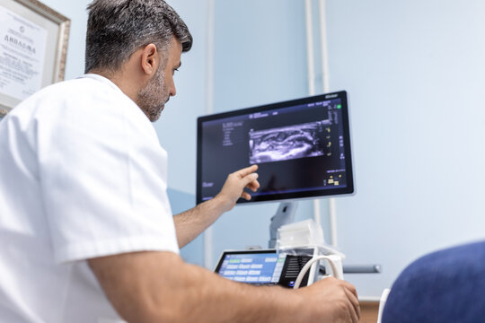 At the medical clinic, Caucasian male doctor doing the doppler ultrasound test evaluation of arteries and veins on a female patient