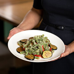 Frozen vegetables onplate in hands of cook. Raw eggplant, asparagus beans. Ingredients for cooking. Freezing and storage of vegetables. Top view.