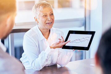 Senior business woman, tablet and data of graph, chart or statistics in meeting at corporate office. Mature female manager showing company investment, profit or annual target and results at workplace
