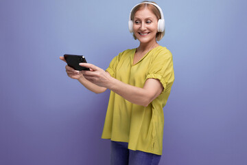 Fototapeta premium joyful blond mature woman watching video on smartphone using headphones