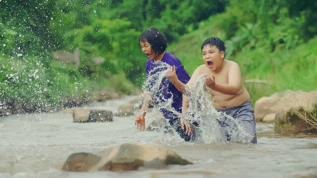 Children playing with friends in the river in the countryside, Boys and girls smiling and happy playing in the water at countryside in Thailand.