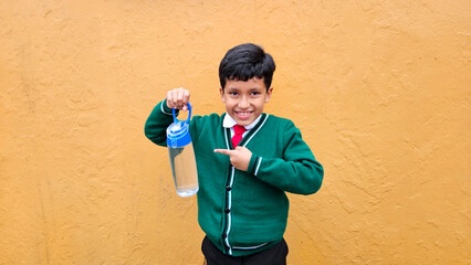 Dark-haired 9-year-old Latino boy in elementary school uniform drinks water because it is important...