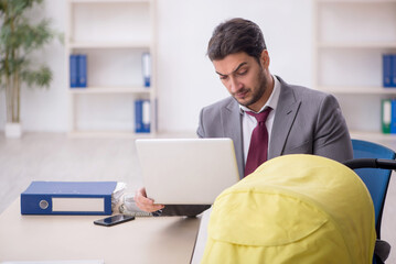 Young male employee looking after newborn at workplace