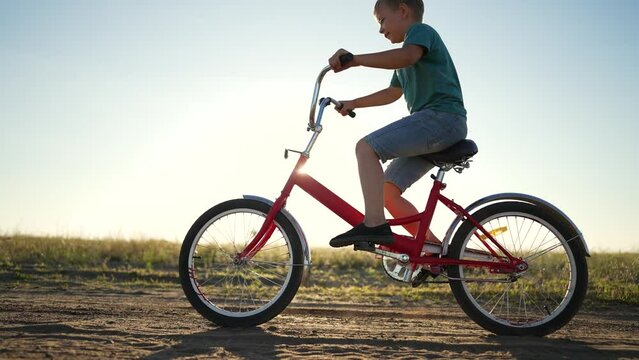 Kid is learning to ride bike. child of family rides bicycle on rural road.happy Kid are everywhere on street.Travel by bike in summer. cheerful kid rides bike in summer park.go everywhere.Happy family