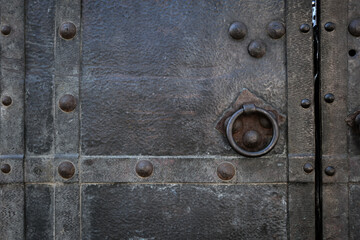 Close-up of an old black iron door with a  handle.