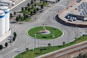 Top View of a Road Traffic Circle and Neighboring Roads Near an Industrial Area with Tree