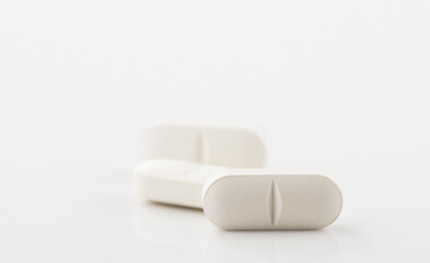 White pills lie on a white surface. Copy space.