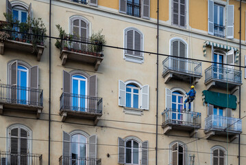 Fototapeta na wymiar Edilizia acrobatica. Lavoratori con corde da scalata al lavoro per riparazioni e ristrutturazioni edifici.