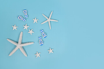 Simple summer banner with white starfish and sandals on blue background with copy space