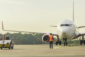 Obraz premium Ground Crew in the signal vest. Aviation Marshall or Supervisor meets passenger airplane at the airport. Aircraft is taxiing to the parking place. Apron movement control officer in safety vest parking