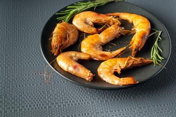 Caridea or boiled shrimps with rosemary in a bowl on a gray table. The idea of delicious dietary seafood for lunch or dinner
