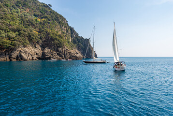 Sailing boats in motion in the blue Mediterranean sea (Ligurian sea) in front of the San Fruttuoso...