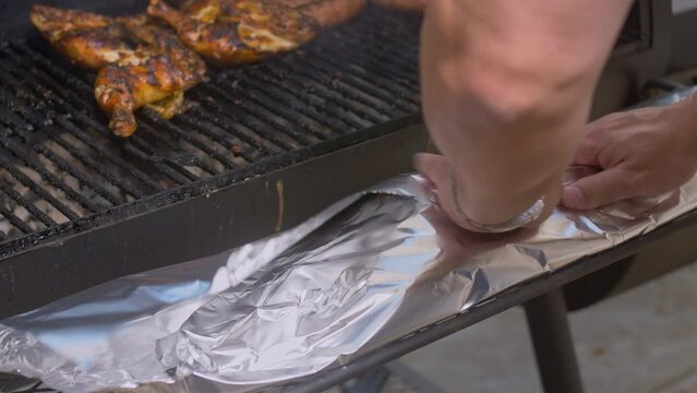 Man foil wraps brown sugar rub coated BBQ ribs and places on pit