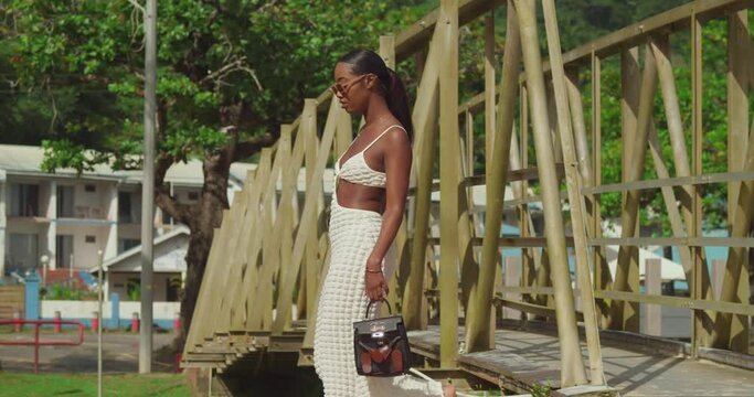 Sexy black girl walking over a bridge on the Caribbean island in a beach dress