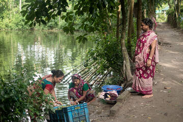 Village women gossiping and cleaning clothes near a pond 