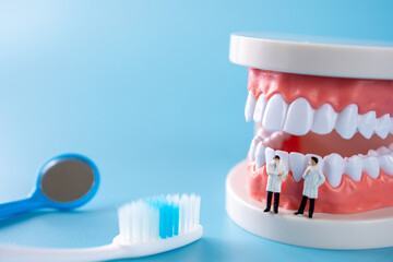 Fototapeta na wymiar miniature two doctor on Toothbrush , teeth model and other items for teeth care on blue background and medical concept on blue background