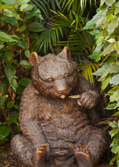 A bronze bear sits in tropical foliage. Travel concept. Wildlife protection. Bear statue in nature