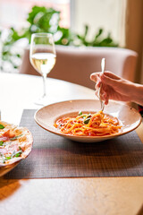 Italian Trattoria. Woman eats Italian pasta with tomato, meat. Spaghetti Bolognese wind it around a...